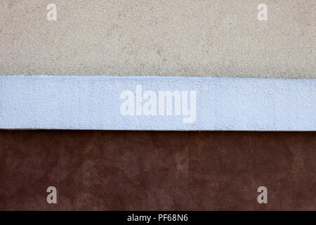 Close-up detail of exterior plastered in three colors, beige, white and brown house or building wall lit by sun. Construction, renovation, copy space  Stock Photo