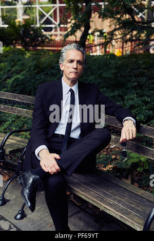 Grey Haired Man in Black Suit Sits on Park Bench Stock Photo