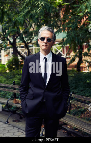 Grey Haired Man in Black Suit Walks Thru a Park Stock Photo