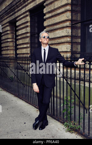 Grey Haired Man in Black Suit Walks Thru a Park Stock Photo