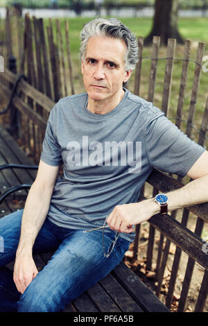 Grey Haired Man Sits on a Park Bench Stock Photo