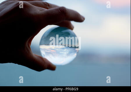 Glass beach on the palm, which reflects the sea .The atmosphere of rest and vacation. Stock Photo