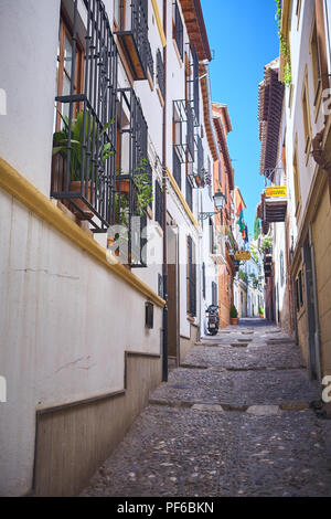 Walking up a narrow empty cobbled traditional street in Granada, Andalucia, Spain in the daytime Stock Photo