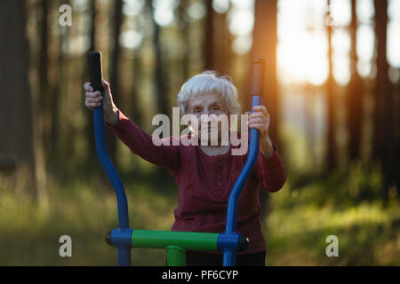 Elderly woman is doing exercises on the playground in the Park. Stock Photo