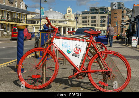 Red bicycle on the esplanade in Porthcawl Wales. The bike is available to hire as part of a bike rental scheme in the town. Stock Photo