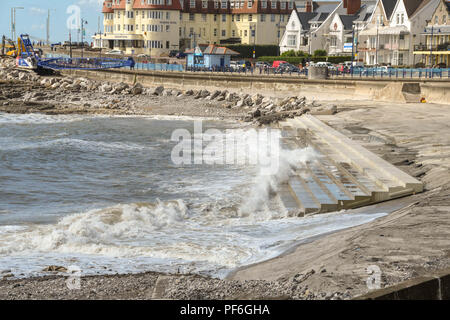 Incoming tide with waves on the seafront in Porthcawl. Wales. The concrete steps are part of improvement works to protect it from the sea. Stock Photo
