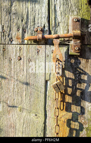 Old lock and chain on weathered barn door - France. Stock Photo