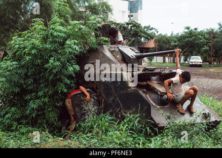 Managua, Nicaragua,  June 1986; Children play on the wrecked remains of Somoza's armoured tanks and APCs  in the centre of Managua. There were destryed by Sandinista forces in civil war against Somoza in 1979. Stock Photo