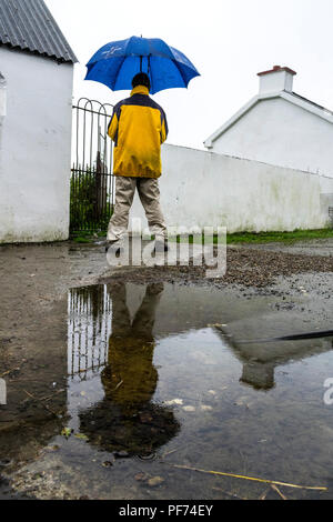 Ardara, County Donegal, Ireland weather. 20th August 2018.  A reflection of a man holding an umbrella in the rain on Ireland's north-west coast. Credit: Anna Hidalgo-Wayman/Alamy Live News Stock Photo