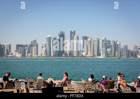 Doha, Qatar - Jan 8th 2018 - Locals and tourists enjoying a cafe bar with Doha's skyline in the background in a blue sky day, Doha in Qatar Stock Photo