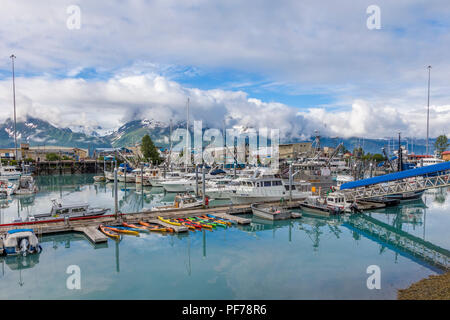 Big white clouds with patches of blue sky over small boat harbor on Prince William Sound in Valdez Alaska Stock Photo