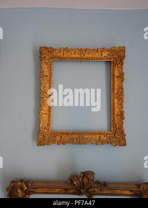 Single gold picture frame with no pictures in the frame hanging on a wall with plain background. Property released Stock Photo