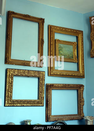 Large collection of Gilt Gold picture frames with no pictures in the frames  hanging on walls with plain background. Property released Stock Photo