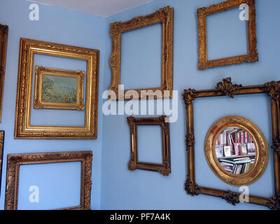 Large collection of Gilt Gold picture frames with no pictures in the frames  hanging on walls with plain background. Property released Stock Photo