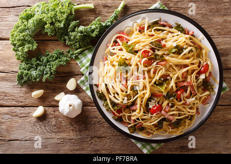 Italian food: pasta linguine with fried bacon, vegetables and parmesan cheese close-up on a plate on a table. horizontal top view from above Stock Photo