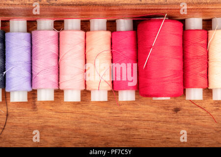 An overhead closeup photo of vibrant red sewing thread spools in a wooden box with copyspace Stock Photo