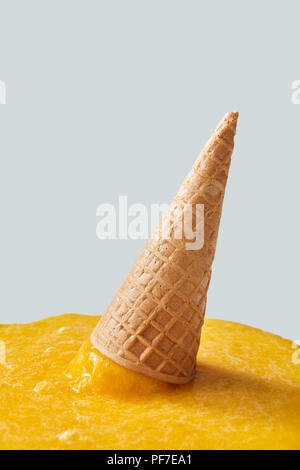 Splashes of fruit ice cream on a gray background. Falling crispy waffle cone of ice cream. Copy space for text Stock Photo