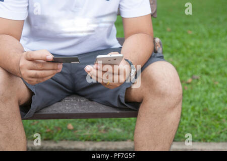 Close up hands holding credit card and using mobile smart phone outdoor, Online shopping. Stock Photo