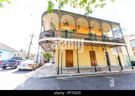 New Orleans, USA - April 23, 2018: Old town street in Louisiana famous town, city, cast iron balcony wall corner yellow colorful building nobody durin Stock Photo