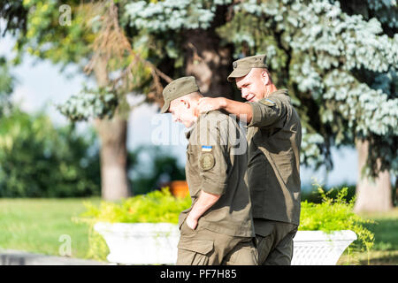 Kyiv, Ukraine - August 12, 2018: Two happy young Ukrainian army soldiers men guys friends walking in park in Mariinskyi Park, Kiev embracing arm aroun Stock Photo