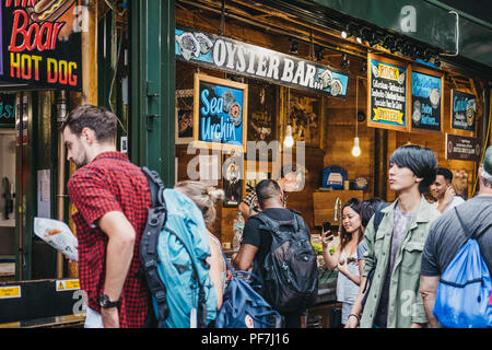 London, UK - July 24, 2018: Seller and customer at an oyster bar in Borough Market, one of the largest and oldest food markets in London. Stock Photo