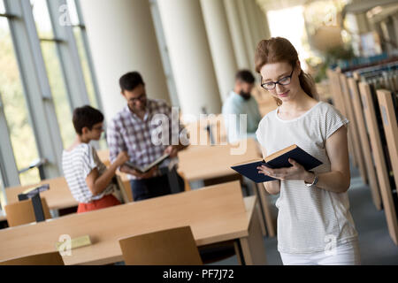 Female student reading a book at library Stock Photo