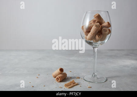A transparent glass with sweet waffle rolls on a gray background and copy space. Stock Photo