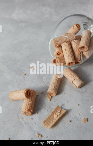 Crispy dessert - waffle rolls lie in a glass on a gray background. Top view Stock Photo