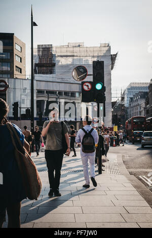 People walking near Tottenham Court Road, London, at sunset. Tottenham Court Road is a London Underground and a future Elizabeth Line stop. Stock Photo