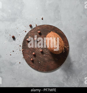 Whole tropical fruit coconut with chocolata balls on a round wooden board ona gray stone table. Stock Photo