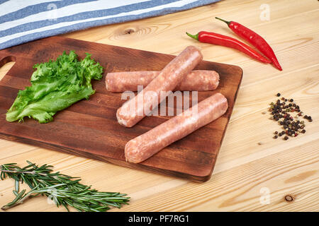 Raw sausages with vegetables and spices on wooden background Stock Photo