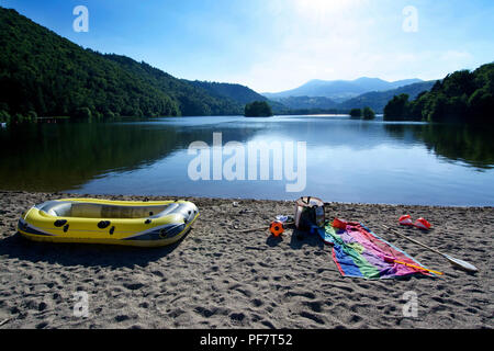 Rubber boat, towel and beach objects laid on the beach of Lake Chambon. Puy de Dome.  Auvergne-Rhône-Alpes.France Stock Photo