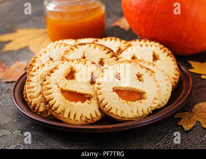 Homemade  cookies in the form as Halloween  jack-o-lantern pumpkins  on the dark table. Stock Photo