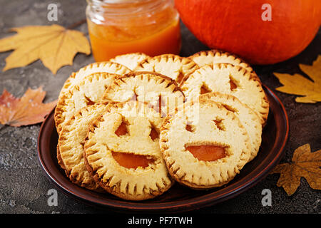 Homemade  cookies in the form as Halloween  jack-o-lantern pumpkins  on the dark table. Stock Photo