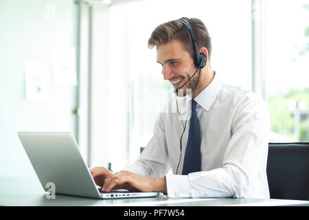 Happy young male customer support executive working in office. Stock Photo