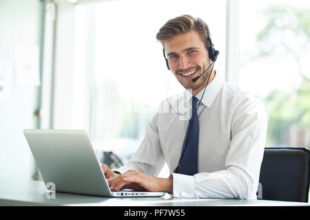 Happy young male customer support executive working in office. Stock Photo