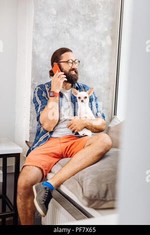 Handsome man laughing while speaking by the phone Stock Photo