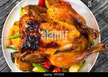 Roasted whole chicken, potatoes, baby carrots, eggplants, green beans, close-up Stock Photo