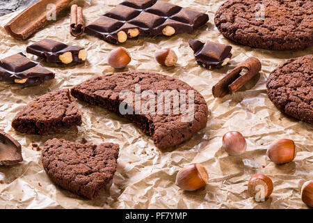 Chocolate cookies, chocolate with hazelnuts on a parchment paper, close-up Stock Photo