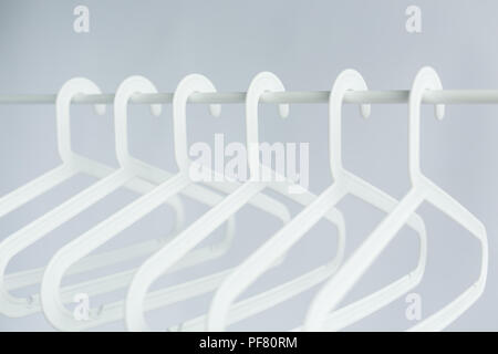 clothing, costume and accessories concept - plastic hangers on a rod on white background Stock Photo