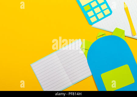 School education papercut background. School bag backpack, books notebooks and calculator paper cut on yellow background. Top view Stock Photo