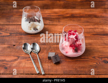 Two portions of vanilla and strawberry ice cream in glass on wooden table Stock Photo