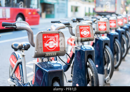London, UK - June 22, 2018: Many Santander Cycles red bikes for hire, rent, rental standing, parked at docking station in downtown in row by street, r