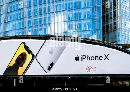 London, UK - June 22, 2018: Advertisement Billboard for iPhone X and Virgin Media on highway road bridge behind modern skyscraper building Stock Photo