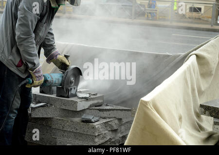 The worker cuts a big powerful angle grinder paving slabs. Stock Photo