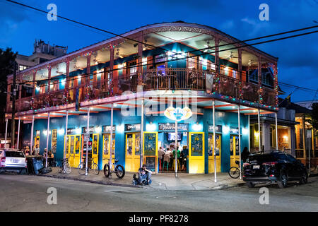 New Orleans, USA - April 22, 2018: Restaurant Dat Dog selling hot dogs with people sitting, eating, beggars on street, road at night, evening, blue ho Stock Photo