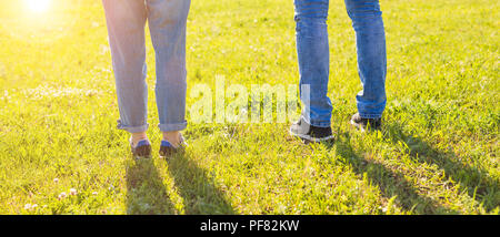 Travel together concept - stylish couple legs on sunny grass in meadow in summer Stock Photo