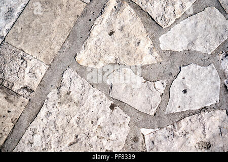The texture of a chaos mosaic made of concrete tiles. Background image of a small area of old street gray tiles. Public pave way. Street paving slabs. Stock Photo