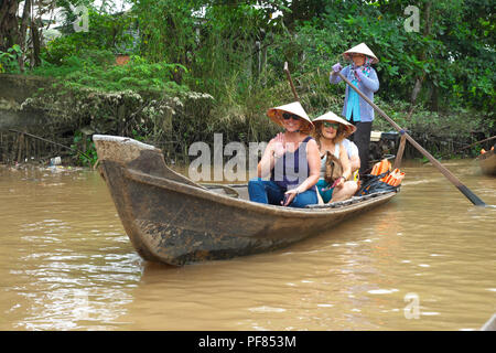 Vietnam tourists taking a boat trip near tCai Be in the Mekong Delta region of Viet Nam with local old woman rowing Stock Photo