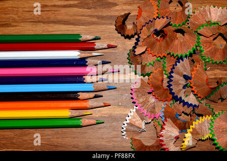 Color pencils and their shavings on a wooden board. Stock Photo